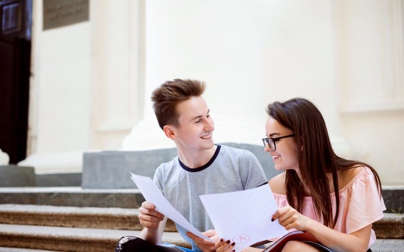 Happy university students share results of final test. Both have received the highest mark for their examination