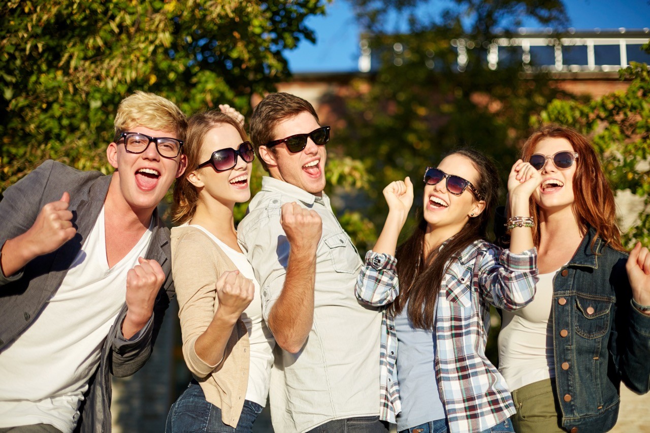 summer holidays, friendship, achievement and success concept - group of happy friends showing triumph gesture at campus or city park